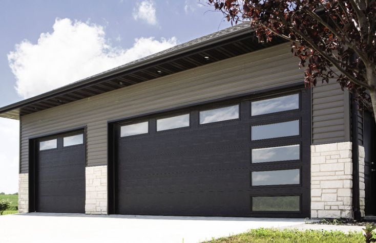 two garage doors are open on the side of a house with grass and trees in front