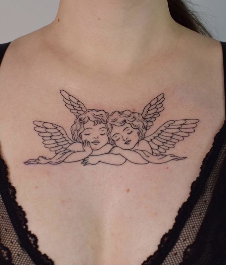 a woman's chest with an angel tattoo on her left shoulder and two cherubs in the middle