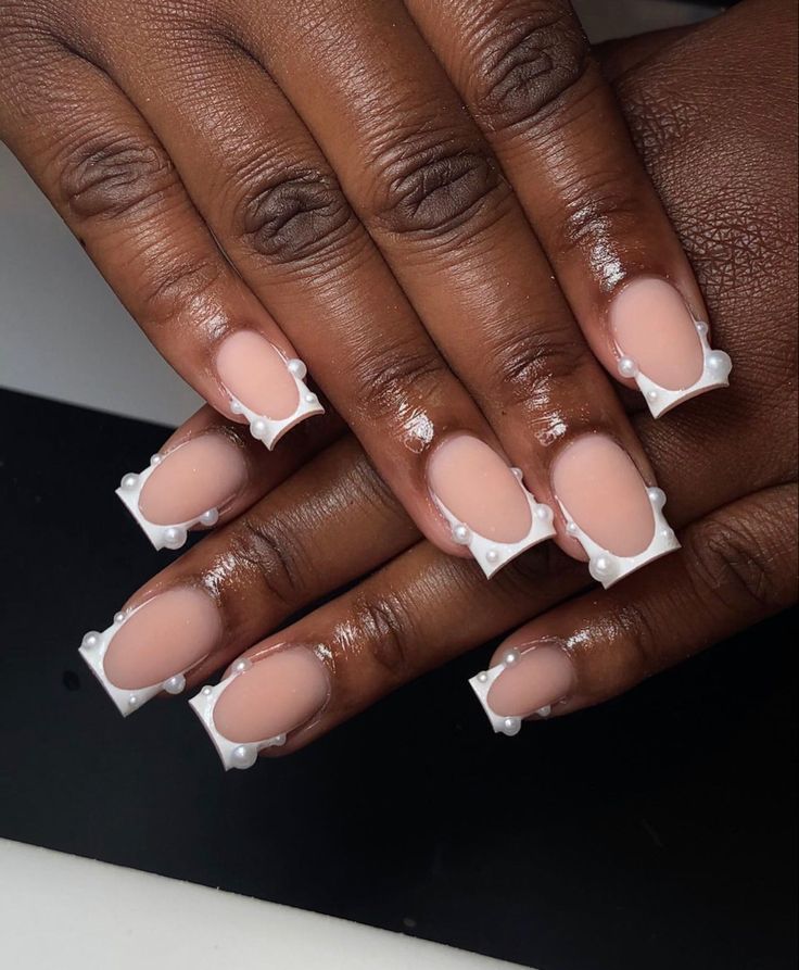 a woman's hands with pink and white manies on their nails, one is holding