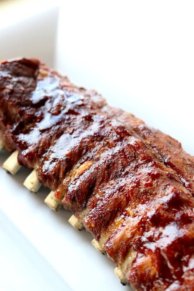 ribs covered in bbq sauce and toothpicks sitting on a white platter