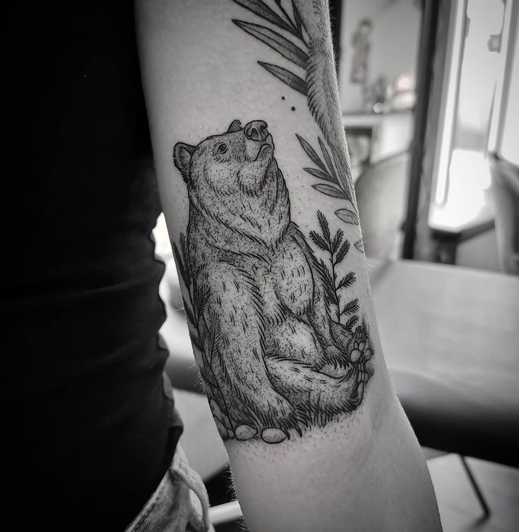 a black and white photo of a bear with leaves on it's back arm