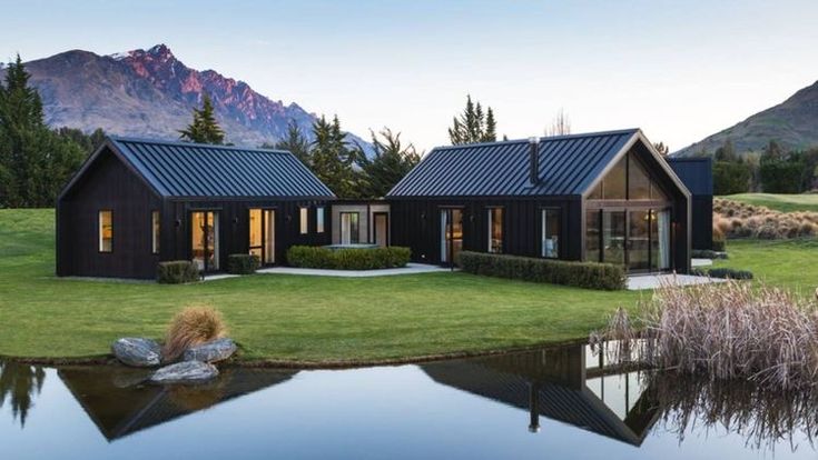 a house with a pond in front of it and mountains in the backround