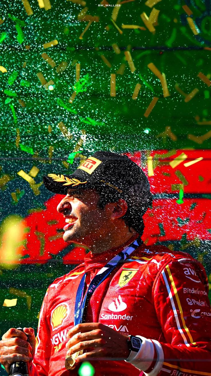 a man standing under confetti on top of a green and red background with confetti in the air