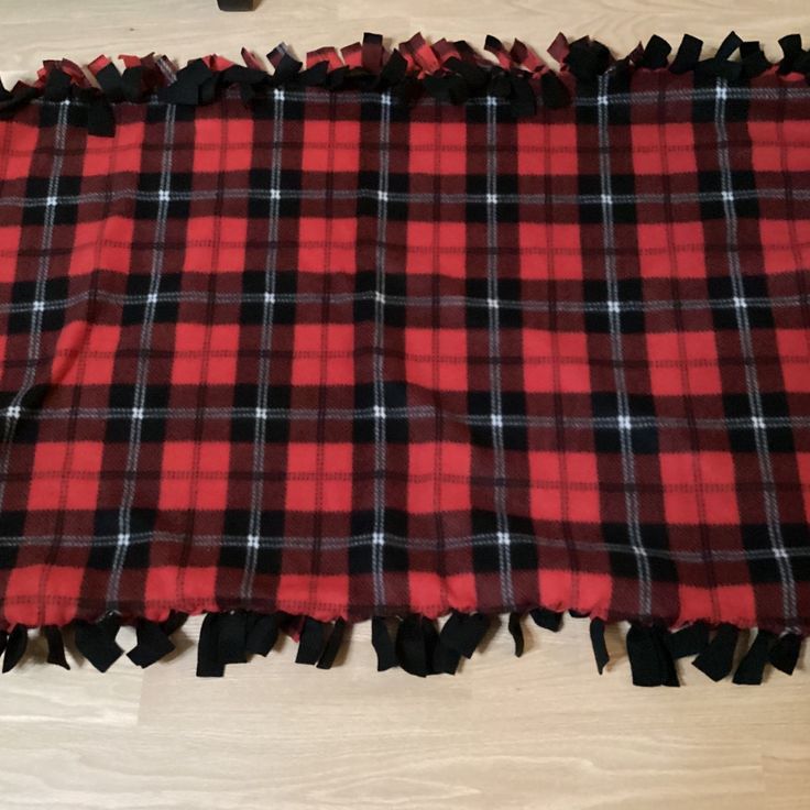 a red and black plaid blanket laying on top of a wooden floor