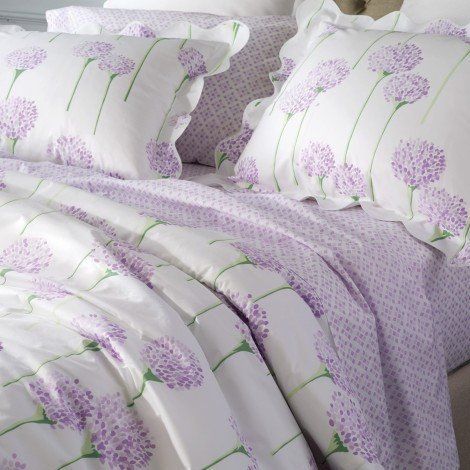 a bed with purple flowers and white sheets