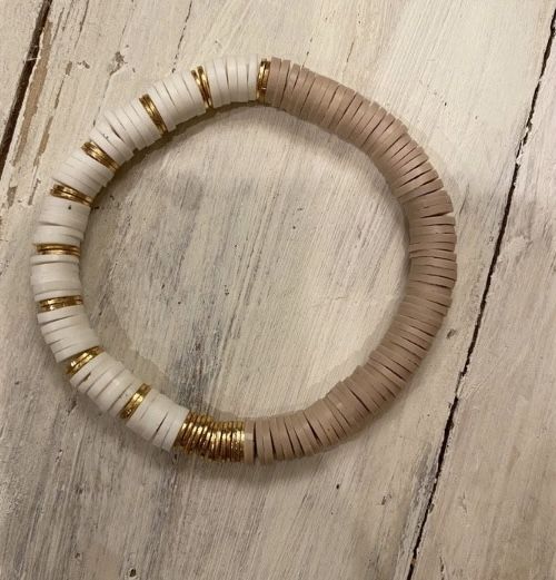 a white and gold beaded bracelet on a wooden surface