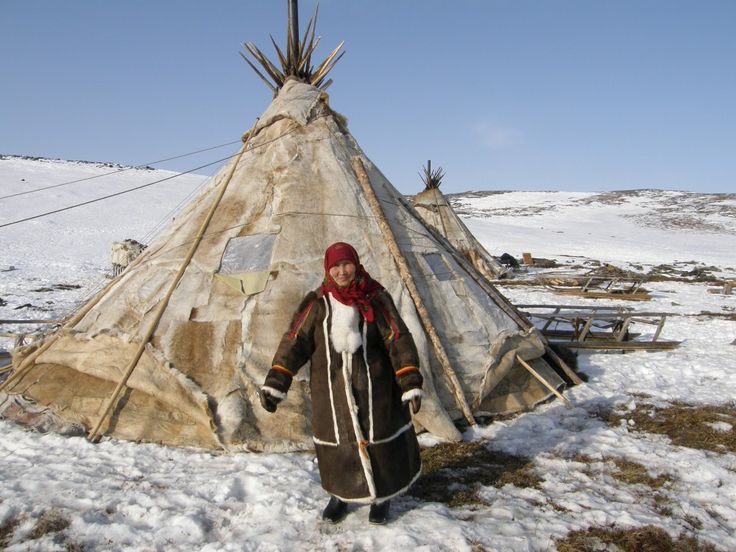 a person standing in front of a teepee with snow on the ground behind it