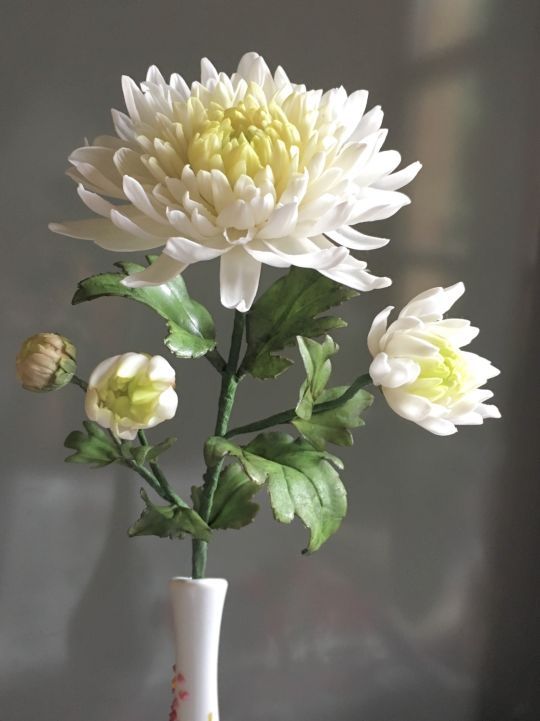 a white vase filled with flowers on top of a table