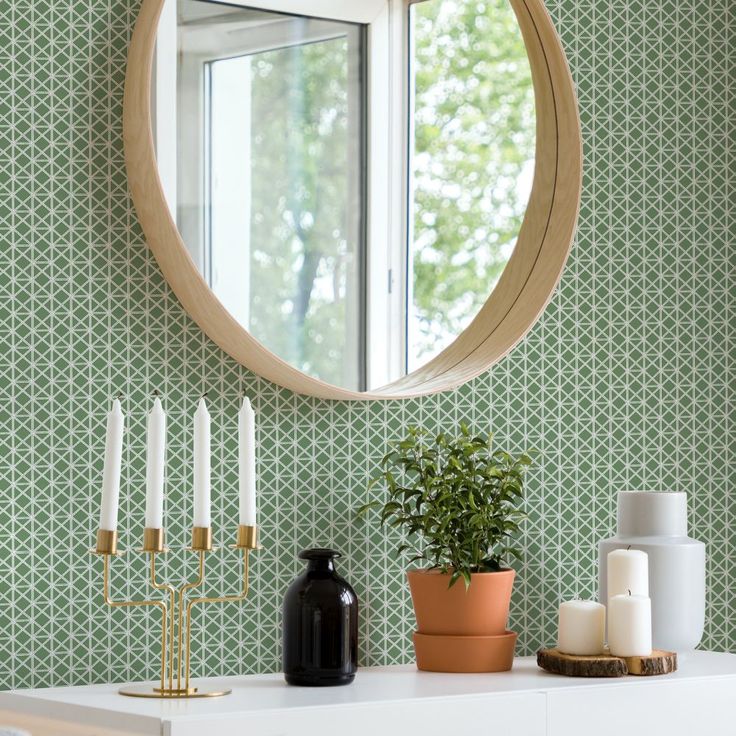 a white dresser topped with a mirror next to a potted plant and candle holder