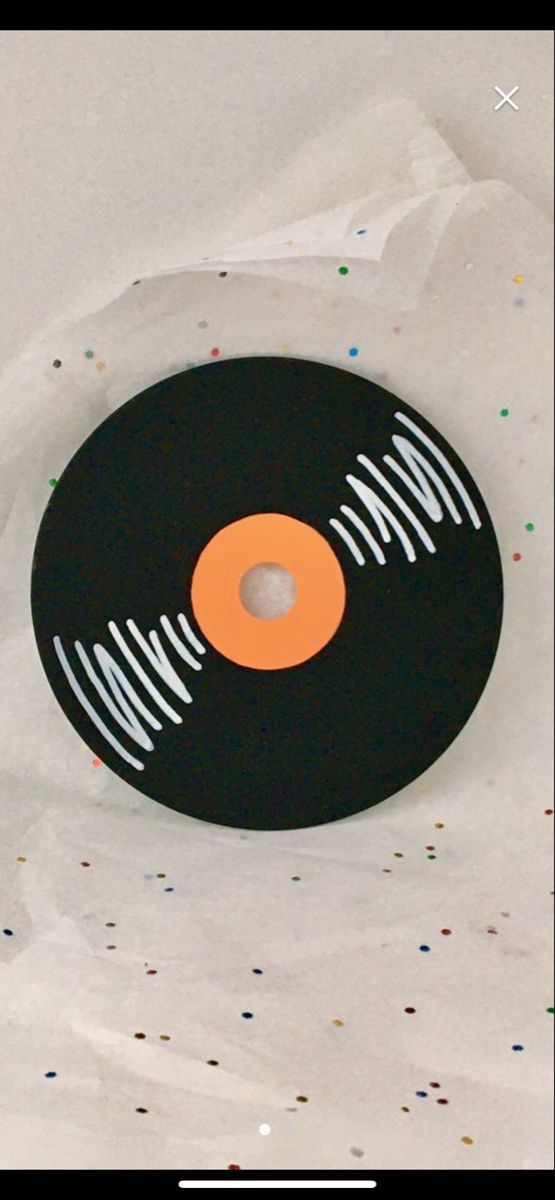 a black record with an orange center and white stripes on the side, surrounded by confetti