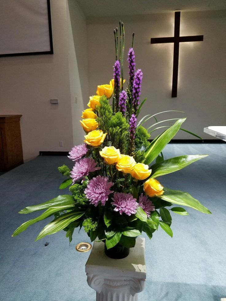 a vase filled with yellow and purple flowers on top of a blue carpeted floor