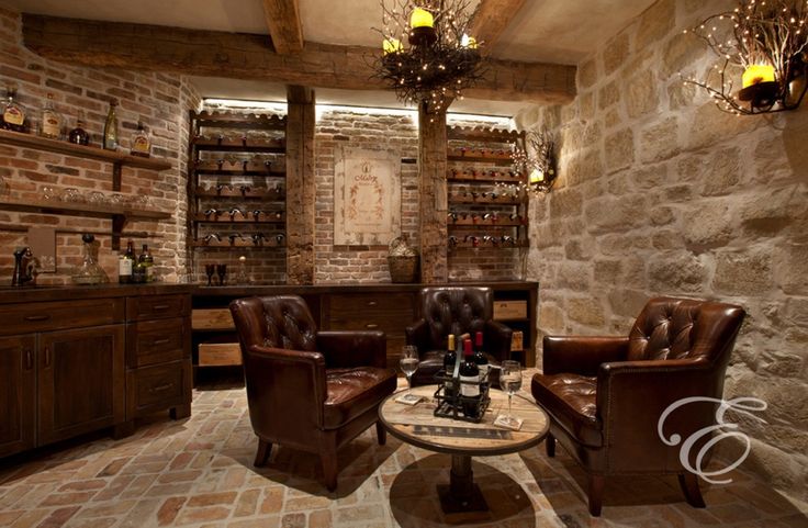 a living room with two brown chairs and a table in front of a stone wall