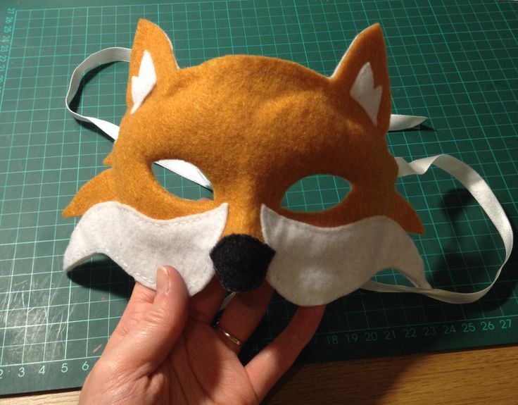 a person is holding up a mask made out of felt with a fox's head on it