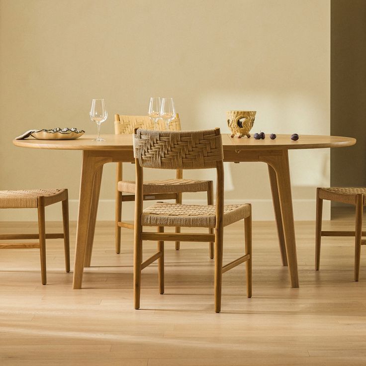 a wooden table with four chairs and a basket on the top, in front of a beige wall