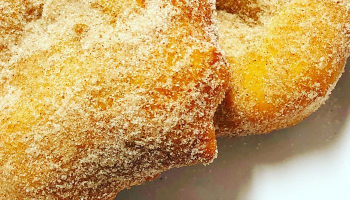 two sugar covered donuts sitting on top of a white plate