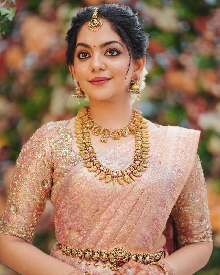 a woman in a pink sari and gold jewelry