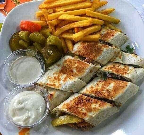 a white plate topped with cut in half sandwiches next to french fries and pickles