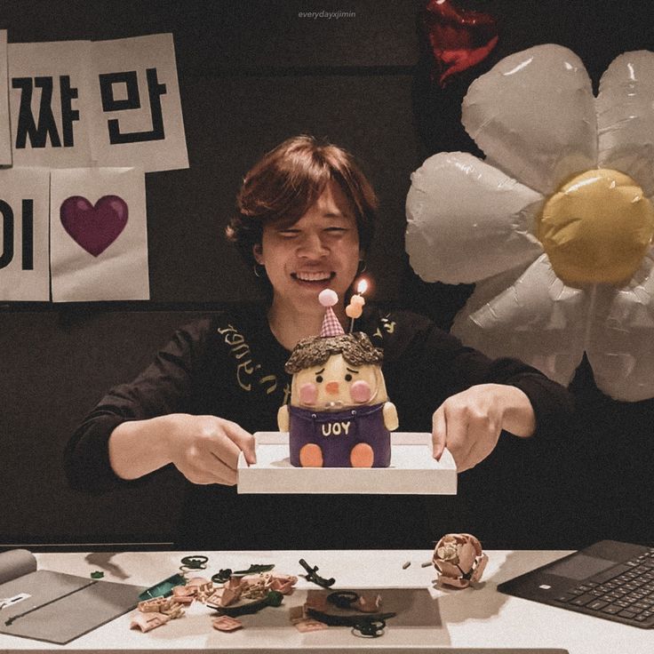 a woman blowing out the candles on her birthday cake in front of balloons and flowers