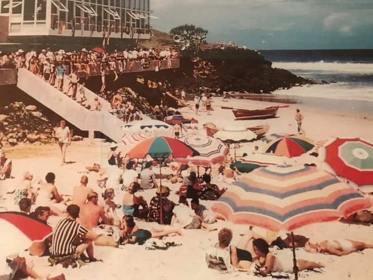 many people are on the beach with umbrellas