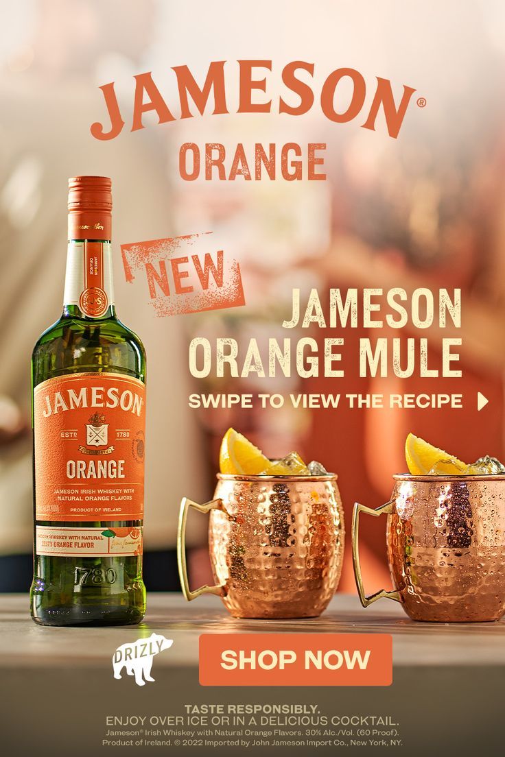 a bottle of jameson orange next to two copper mugs