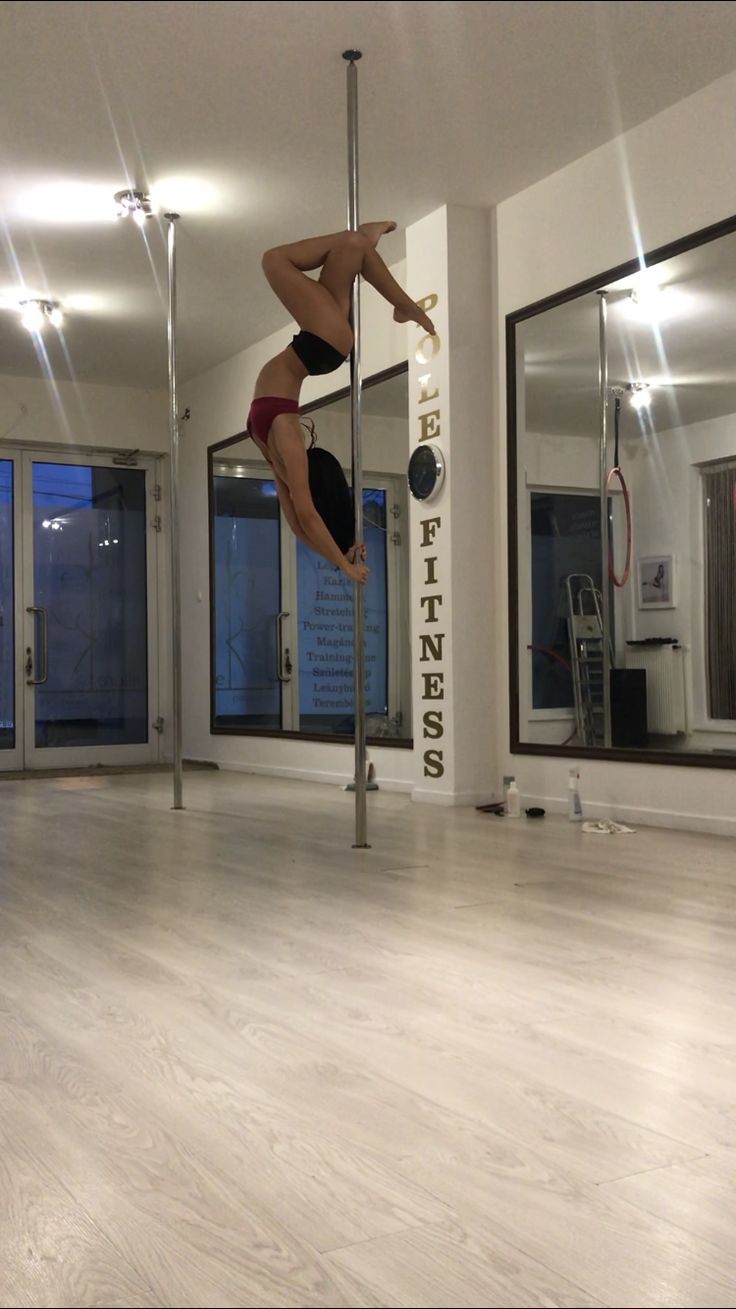 a woman is doing pole dancing in an empty room