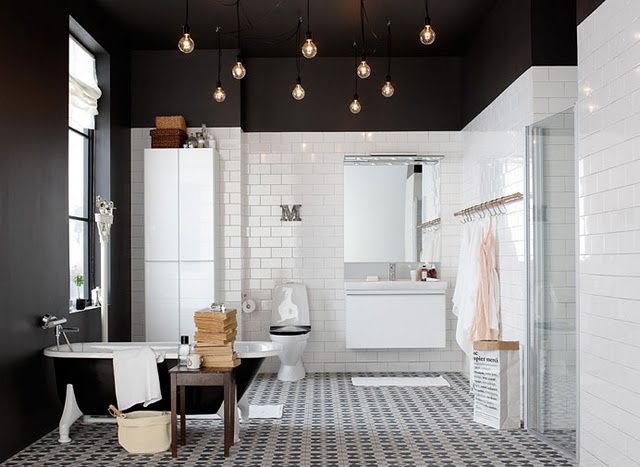 a bathroom with black and white tiles on the floor, lights hanging from the ceiling