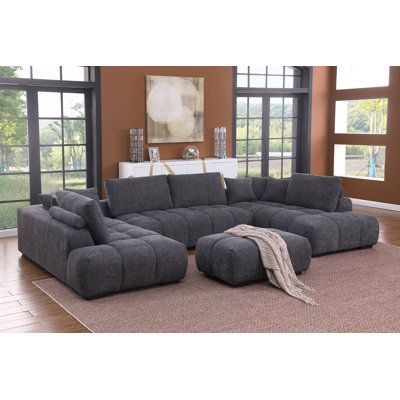 a living room with a large gray sectional couch and matching footstool in front of windows