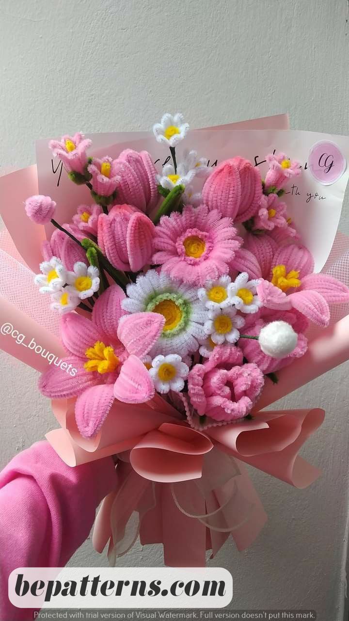 a bouquet of pink and white daisies on top of a pink ribbon tied to a wall