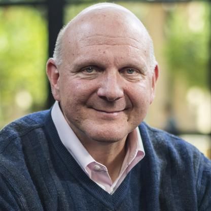 an older man wearing a blue sweater smiles at the camera