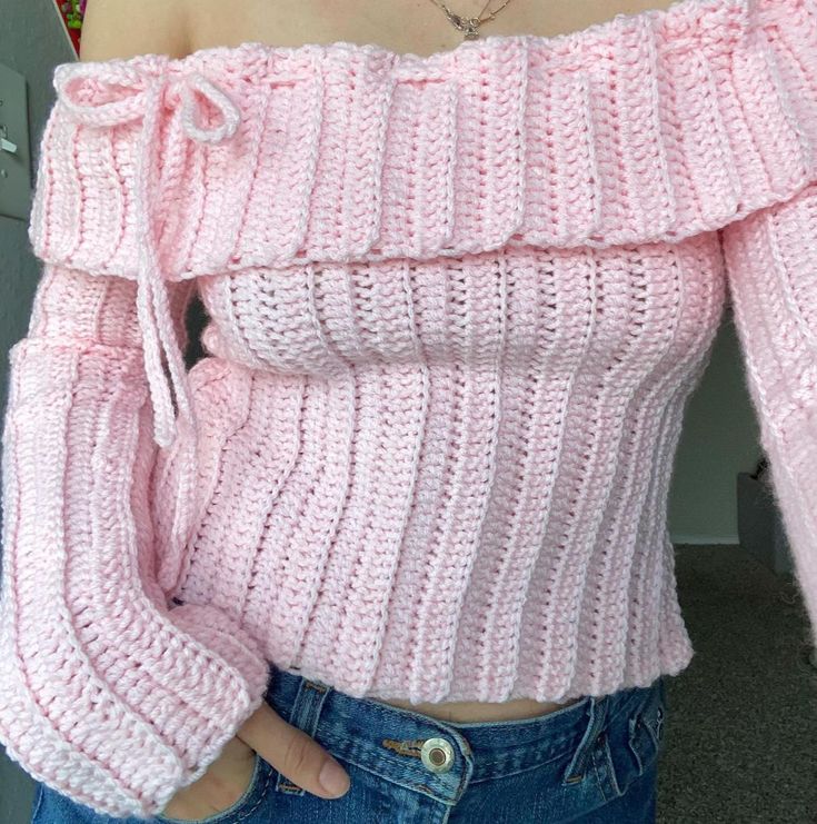 a close up of a person wearing a pink sweater with off the shoulder and sleeves