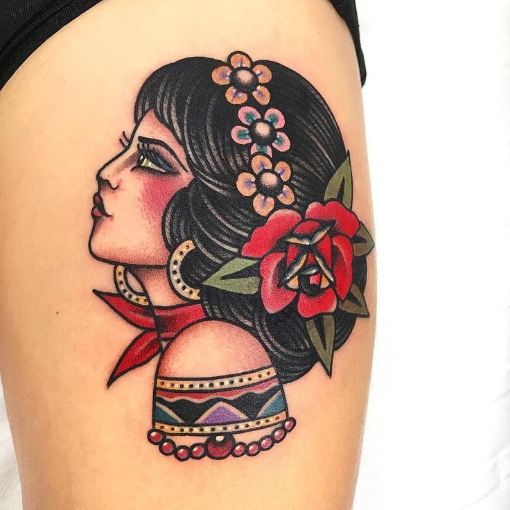 a woman with a flower in her hair tattoo on the side of her thigh,