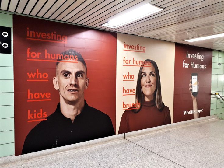 a man and woman are on the side of a building with red signs in front of them