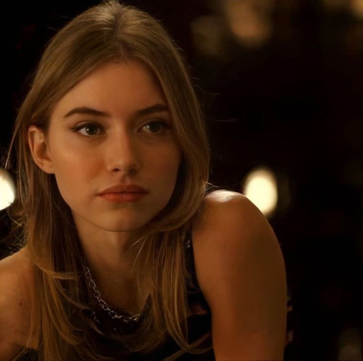 a woman sitting in front of candles looking at the camera with an intense look on her face