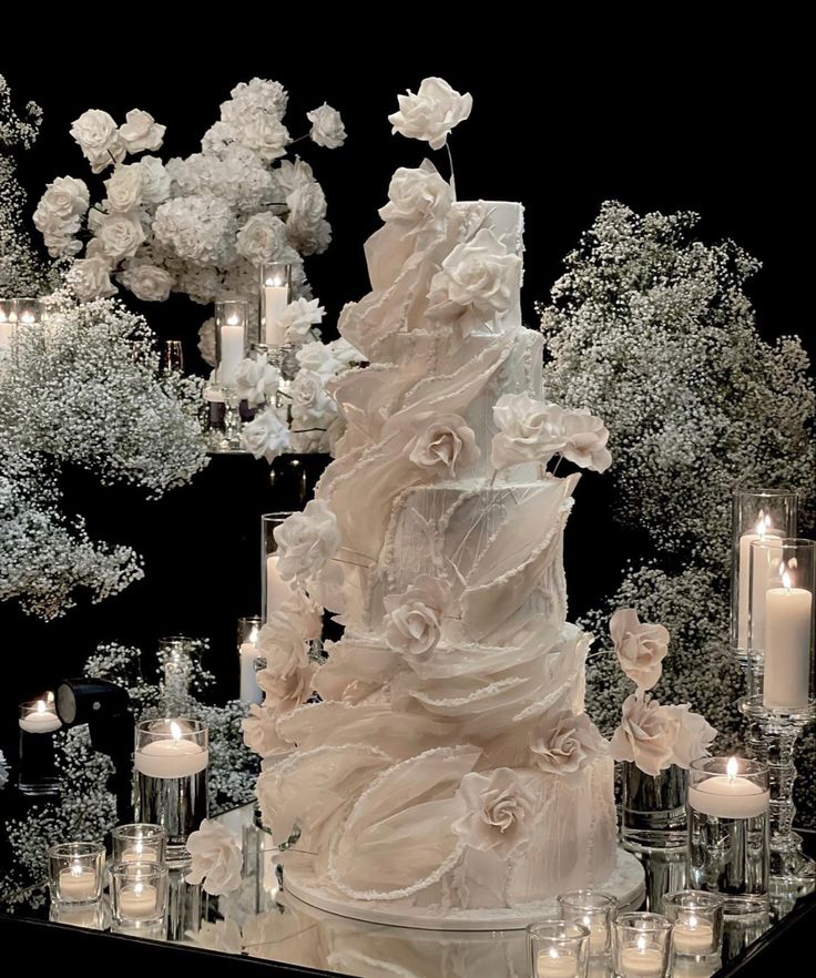 a wedding cake is surrounded by candles and flowers