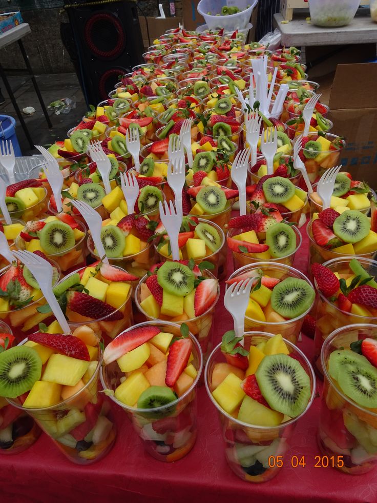 a table topped with lots of fruit cups filled with kiwis and strawberries