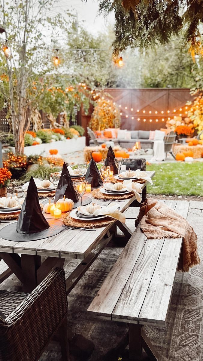 an outdoor table set for halloween with pumpkins and witches hats on it's head