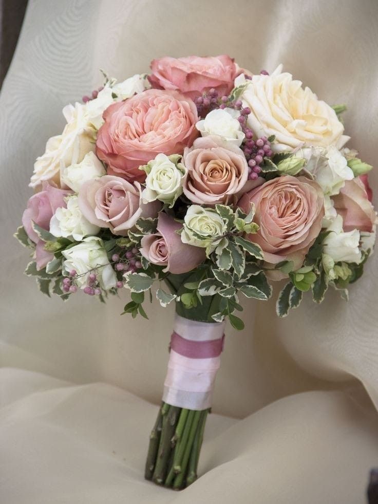 a bridal bouquet with pink and white flowers on a beige clothed chair cover