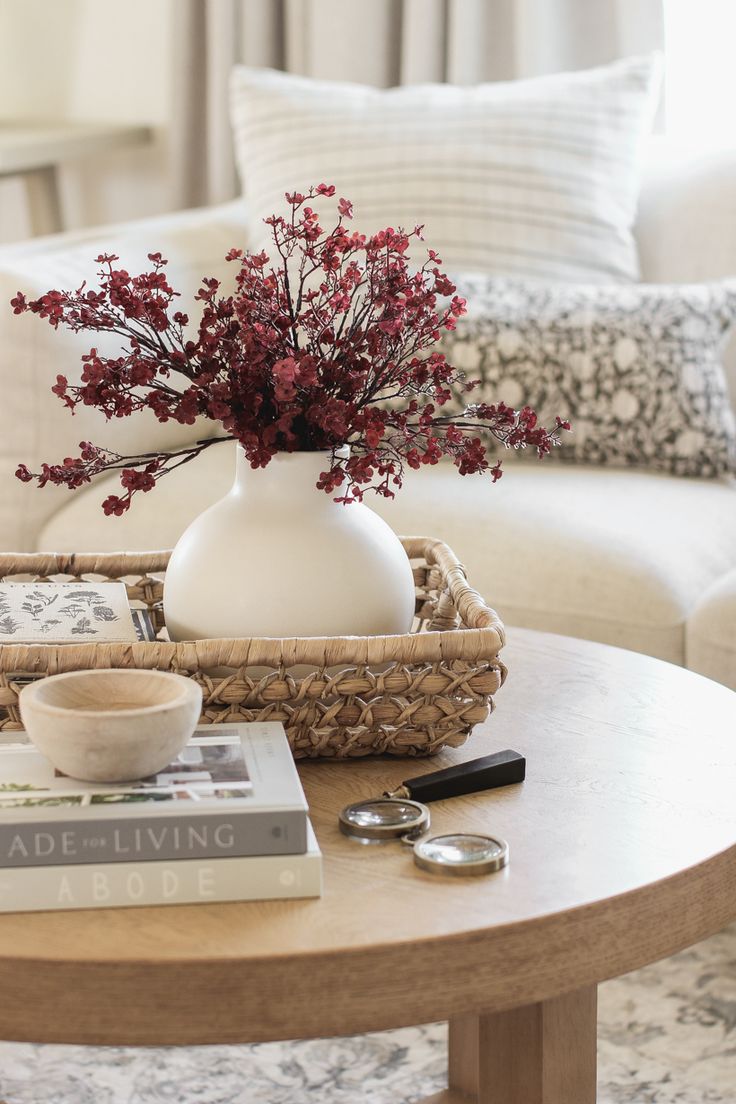 a coffee table with flowers in a white vase and some books on the end tables