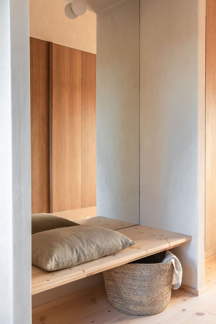 a bed sitting on top of a wooden shelf next to a basket filled with pillows