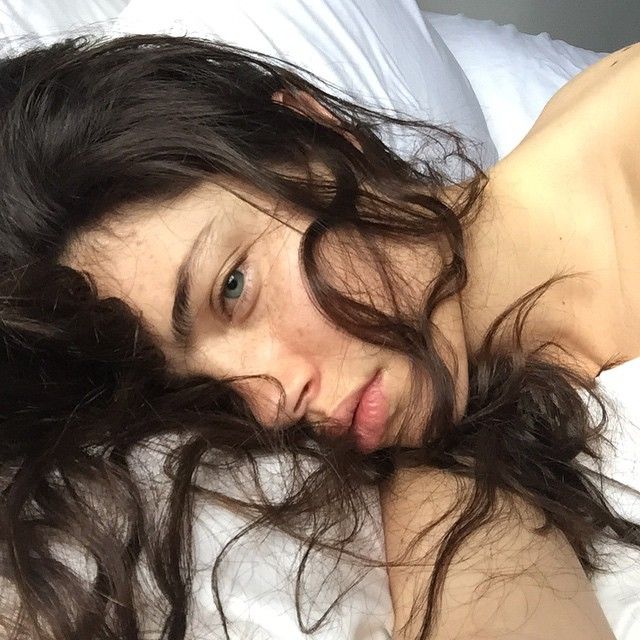 a woman laying on top of a bed next to a white pillow covered in hair