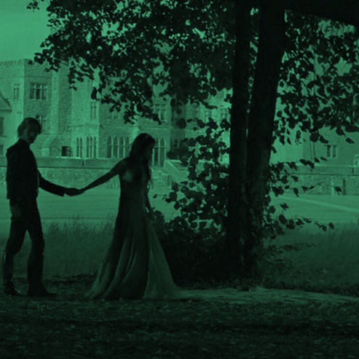 a man and woman are holding hands in front of a tree on a foggy day