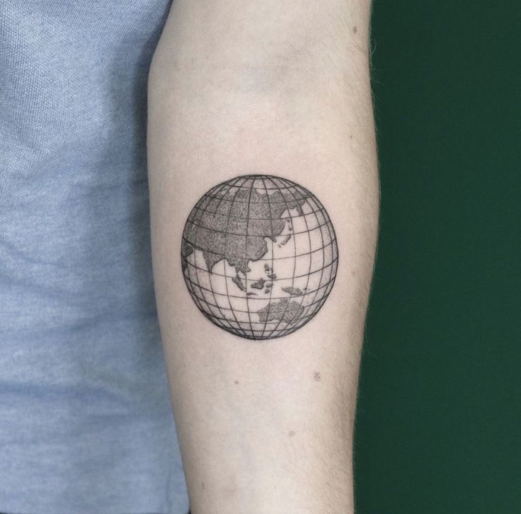 a man's arm with a small globe tattoo on it