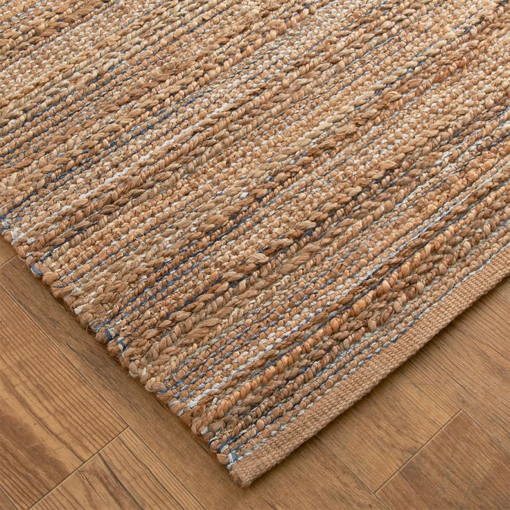 an area rug with brown and blue stripes on the bottom, in front of a wooden floor