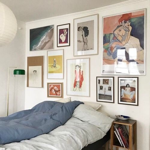 a bedroom with pictures on the wall and an unmade bed in front of it