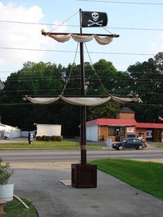 a street sign with a pirate flag on it in front of a building and trees