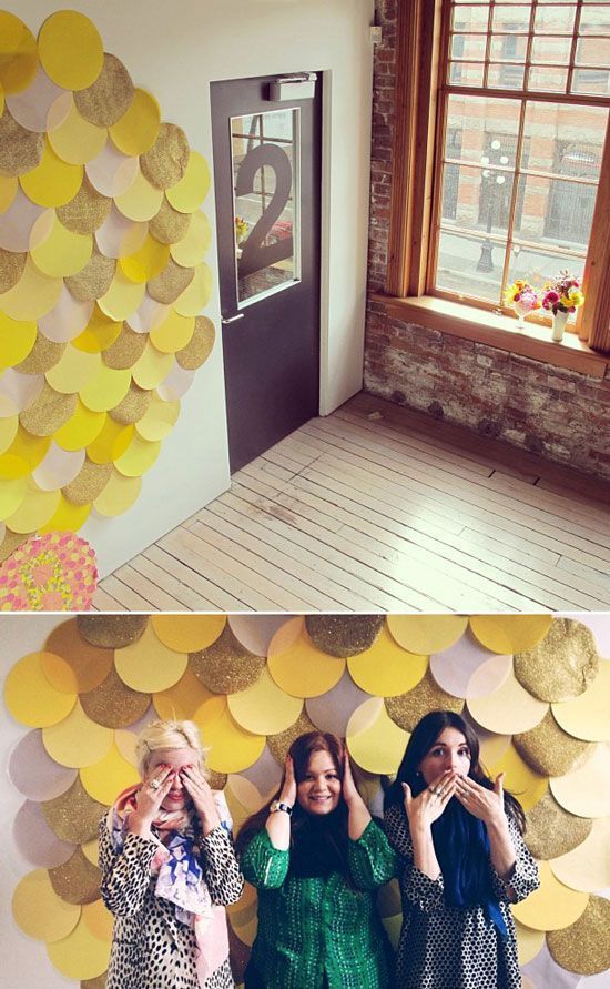 two girls are standing in front of a wall made out of paper circles and the girl is holding her hands up to her face