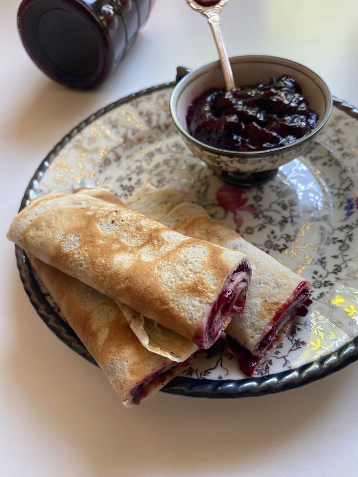 a crepe on a plate next to a bowl of jam