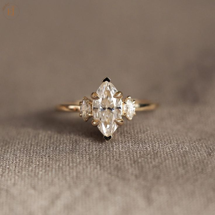 a three stone diamond ring sitting on top of a cloth