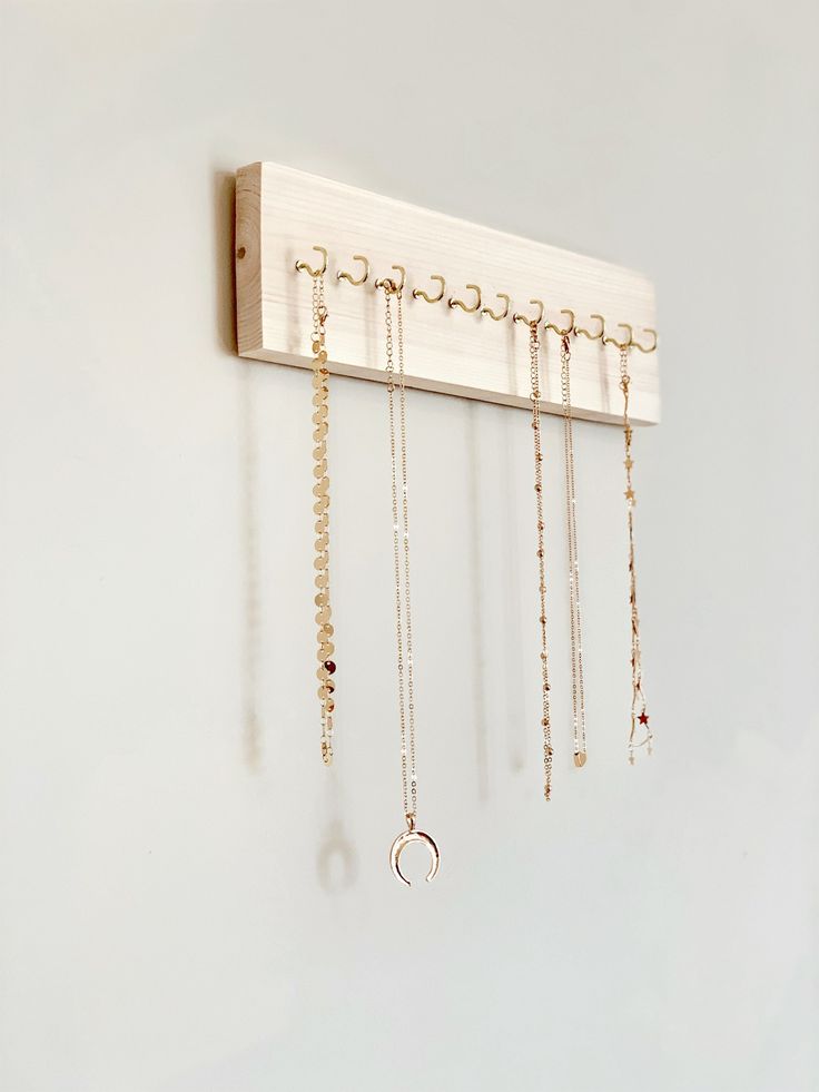 a wall mounted jewelry rack with five pairs of earrings hanging from it