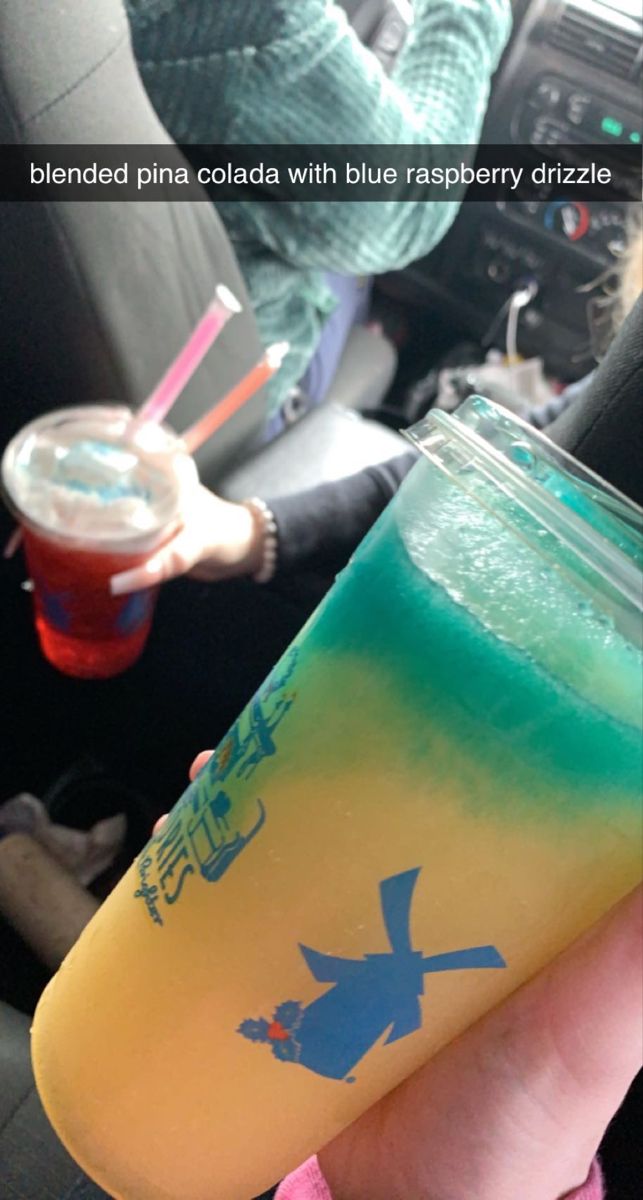 a person holding a drink in their hand with the caption blended pina cola with blue raspberry drizzle